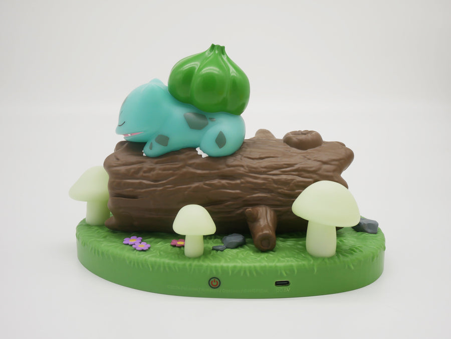 Scène lumineuse Pokémon Bulbizarre endormi sur un tronc d'arbre, entouré de champignons lumineux